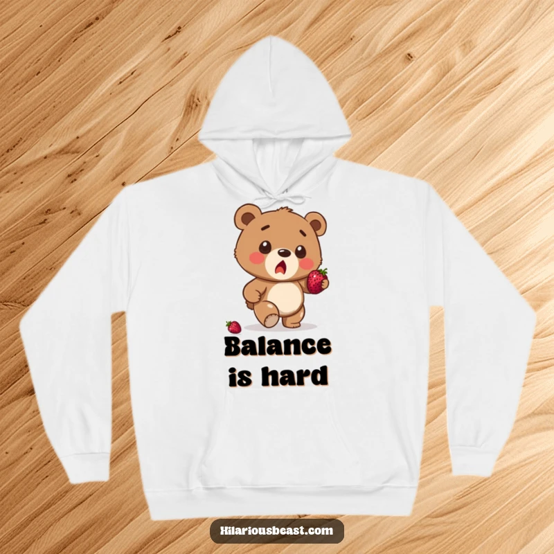 Funny brown bear cub hoodie depicting a surprised cub stumbling, a berry precariously balanced, symbolizing cozy, humorous mishaps.